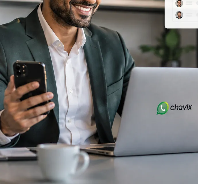 Corretor sorrindo com o celular na mão diante do notebook com o adesivo do Chavix, acompanhando o funil de vendas.